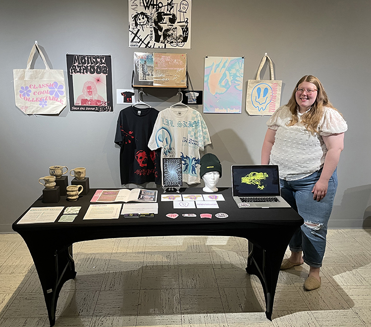 Graphic design student posing with their work